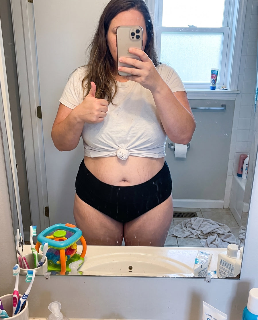 Mom taking a mirror selfie in a black Jadea high-waist brief, thumbs up