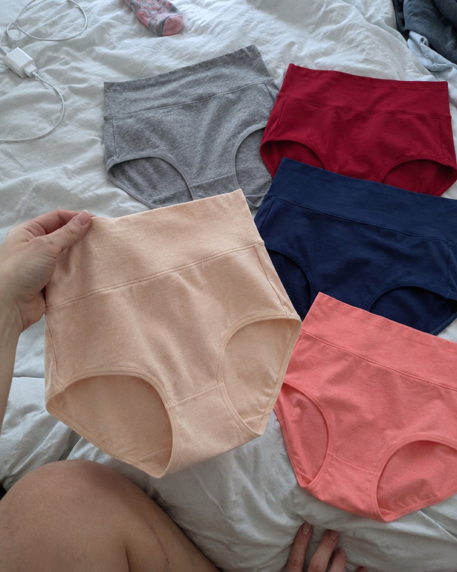 Jadea briefs in five colors spread out on an unmade bed
