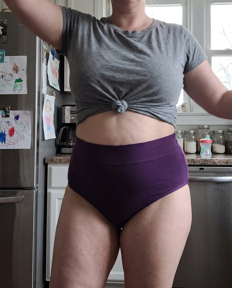 Woman dancing in her kitchen in a deep purple Jadea brief