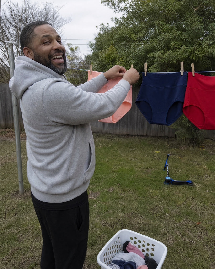 Husband laughing as he hangs Jadea briefs on the clothesline
