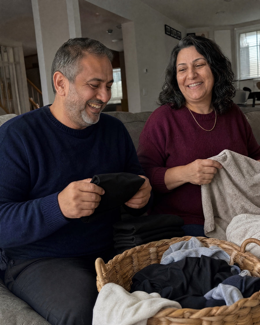 Couple laughing while folding laundry together on the couch